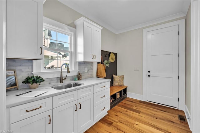 kitchen with white cabinets, light stone countertops, sink, and tasteful backsplash