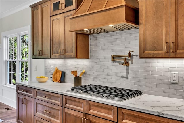 kitchen with dark wood-type flooring, stainless steel gas cooktop, light stone counters, backsplash, and custom exhaust hood