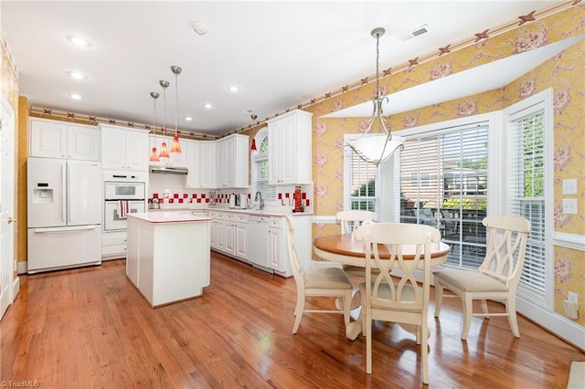 221 Oakmont Park Ct, Kernersville, NC 27284 - kitchen featuring white appliances, wallpapered walls, a center island, plenty of natural light, and light countertops