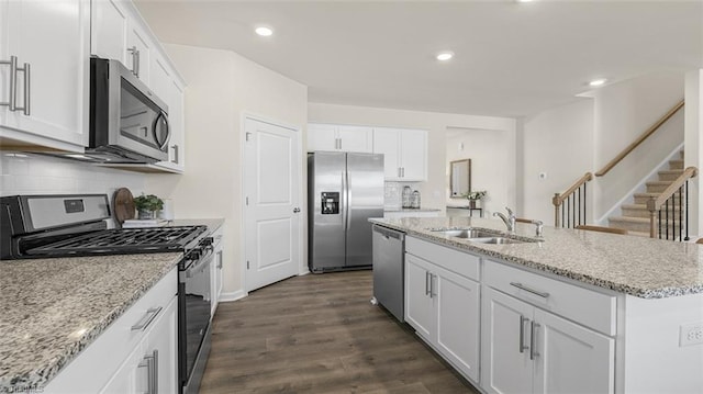 kitchen with sink, stainless steel appliances, white cabinets, and a center island with sink