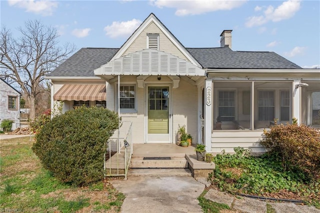 bungalow-style home featuring roof with shingles and a chimney