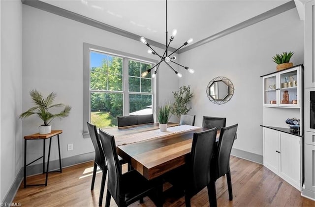 dining space featuring a notable chandelier, ornamental molding, and light wood-type flooring