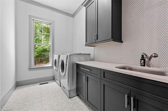 washroom with cabinets, a healthy amount of sunlight, sink, and washing machine and clothes dryer