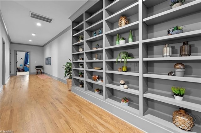 hallway featuring ornamental molding and light hardwood / wood-style flooring