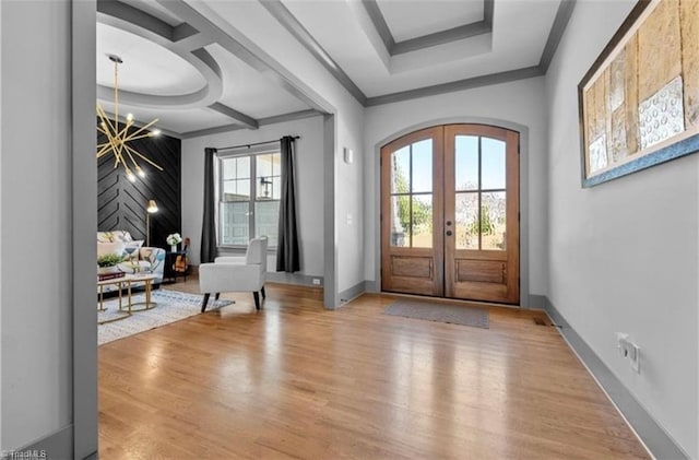 foyer featuring french doors, ornamental molding, an inviting chandelier, and light hardwood / wood-style floors