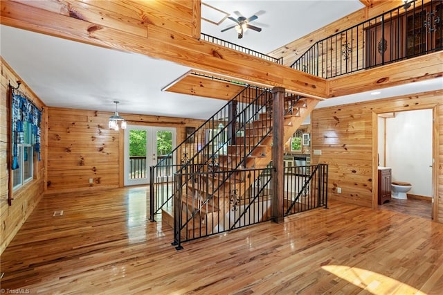 stairs featuring a ceiling fan, wood walls, and wood finished floors