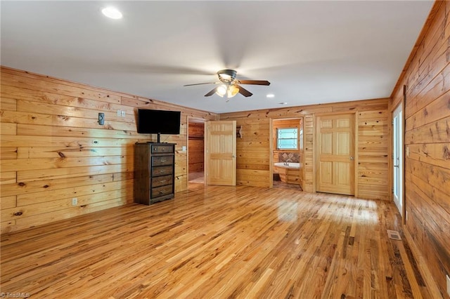 unfurnished bedroom with visible vents, recessed lighting, wood finished floors, and wooden walls