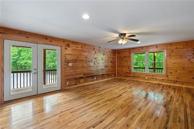 spare room with french doors, a ceiling fan, light wood-style flooring, and a healthy amount of sunlight