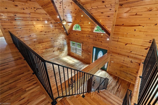 stairs featuring wood-type flooring, wood walls, lofted ceiling with beams, and wooden ceiling