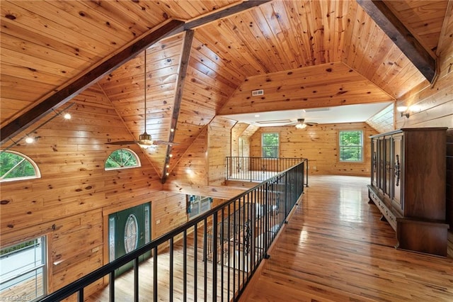 hallway with vaulted ceiling, wood finished floors, wooden ceiling, an upstairs landing, and wooden walls