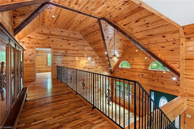 corridor with wooden walls, high vaulted ceiling, wooden ceiling, and wood finished floors