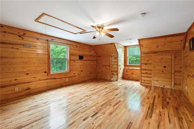 bonus room featuring ceiling fan, wood walls, plenty of natural light, and attic access
