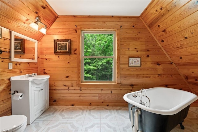 bathroom featuring vanity, wood walls, a freestanding bath, and toilet