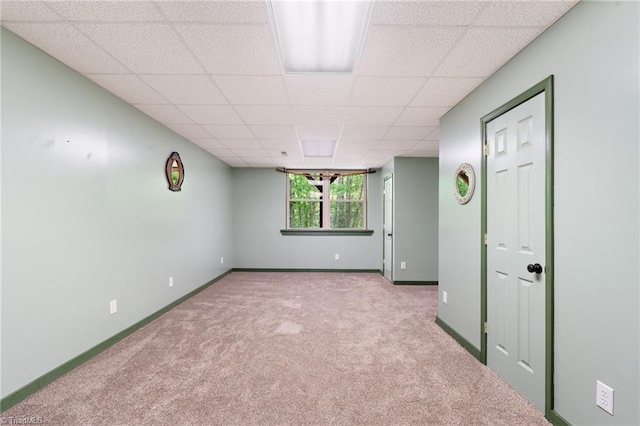 carpeted spare room featuring baseboards and a paneled ceiling