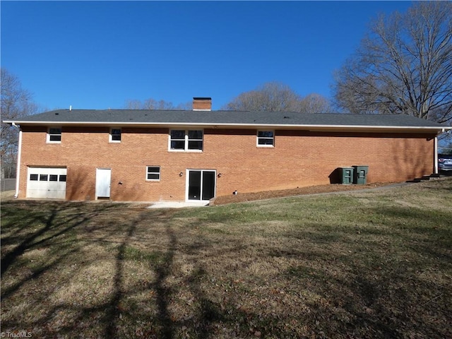 back of property with a garage and a yard