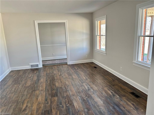 unfurnished room featuring a healthy amount of sunlight and dark hardwood / wood-style flooring