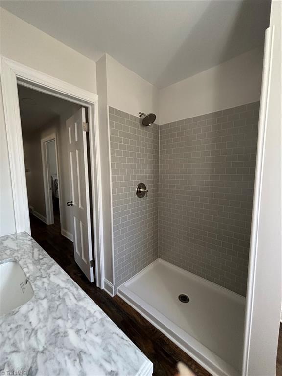 bathroom featuring tiled shower and vanity