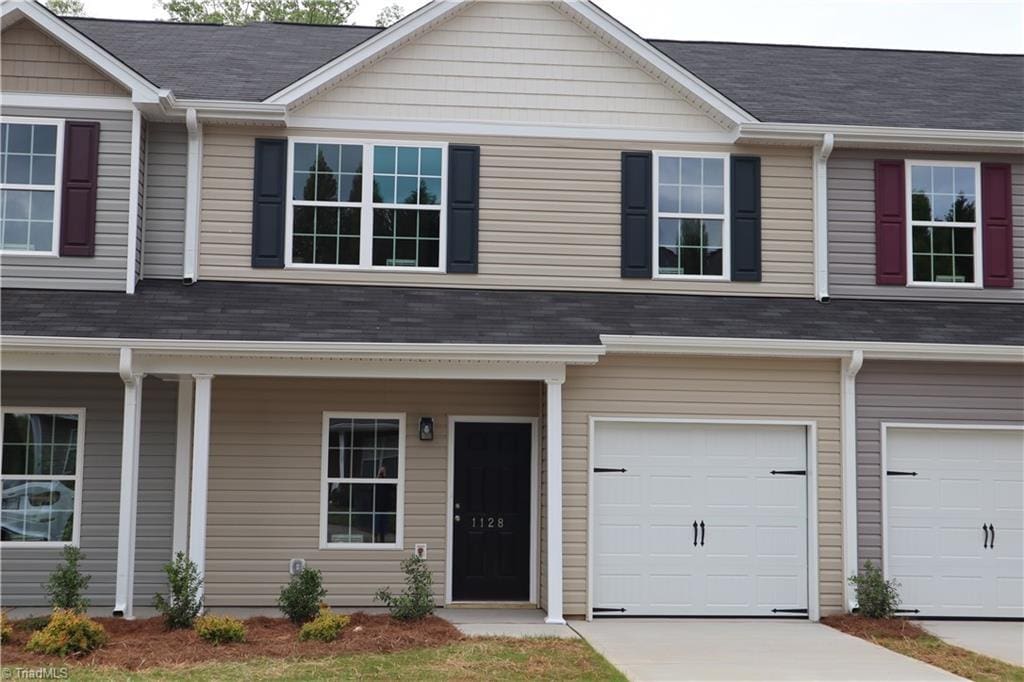 multi unit property featuring concrete driveway, an attached garage, and covered porch