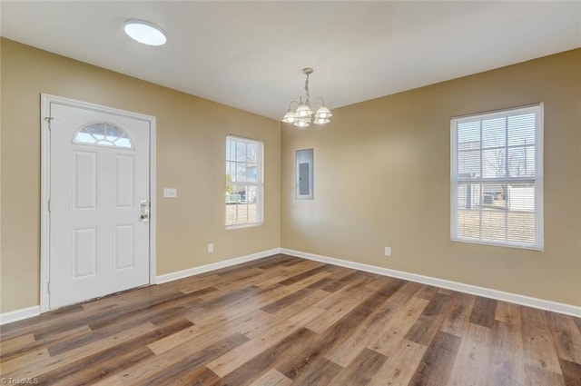 entrance foyer with hardwood / wood-style flooring, a notable chandelier, and electric panel