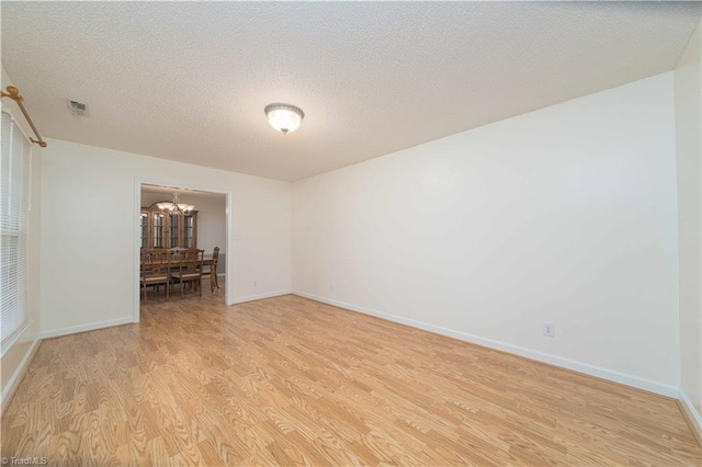 640 Summerest Ct, Kernersville, NC 27284 - empty room with light wood-type flooring, a chandelier, and a textured ceiling