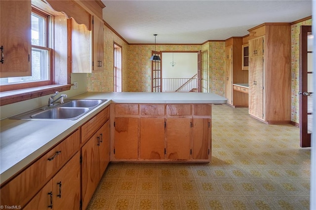 kitchen with kitchen peninsula, pendant lighting, crown molding, and sink