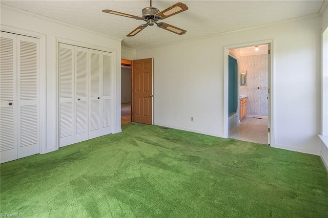 unfurnished bedroom with carpet floors, two closets, ensuite bath, and ceiling fan