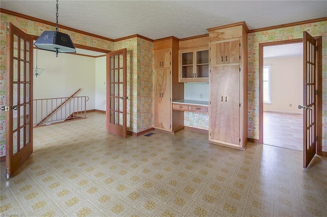 kitchen featuring a textured ceiling, crown molding, hanging light fixtures, and french doors