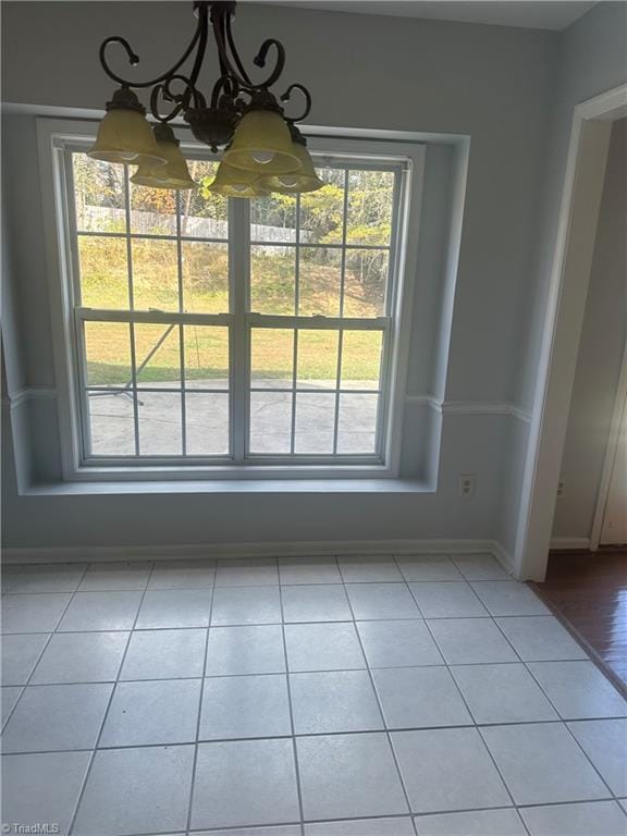 unfurnished dining area featuring light tile patterned floors and an inviting chandelier