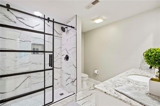 full bathroom with marble finish floors, a marble finish shower, toilet, and vanity