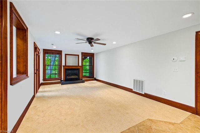 unfurnished living room with recessed lighting, a glass covered fireplace, baseboards, and light carpet