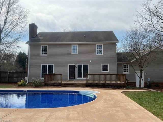 rear view of house featuring a chimney, a fenced in pool, fence, and a wooden deck