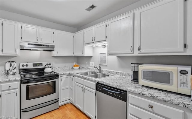 kitchen with appliances with stainless steel finishes, white cabinetry, sink, light hardwood / wood-style floors, and light stone countertops