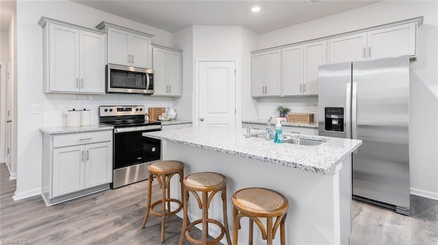 1436 Amberview Ln, Kernersville, NC 27284 - kitchen featuring stainless steel appliances, light wood finished floors, a sink, an island with sink, and baseboards