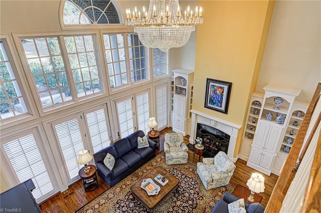 living room with a wealth of natural light, a chandelier, hardwood / wood-style floors, and a towering ceiling