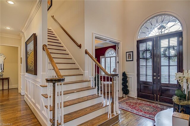 foyer with a high ceiling, french doors, hardwood / wood-style floors, and ornamental molding