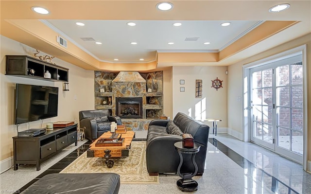 tiled living room featuring ornamental molding, a fireplace, and a tray ceiling