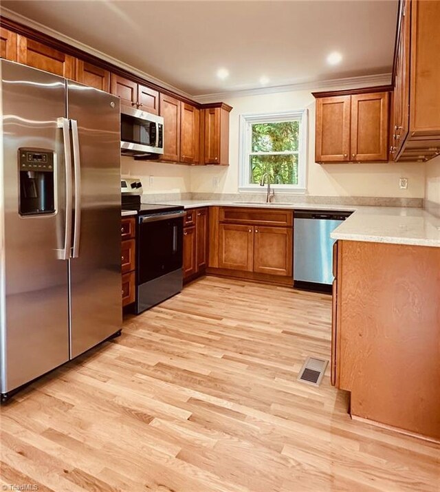 5670 Plantation Dr, Winston-Salem, NC 27105 - kitchen featuring stainless steel appliances, a sink, light wood-style flooring, brown cabinets, and ornamental molding