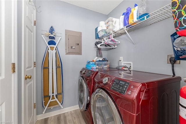 laundry room with washer and dryer, electric panel, and light wood-type flooring