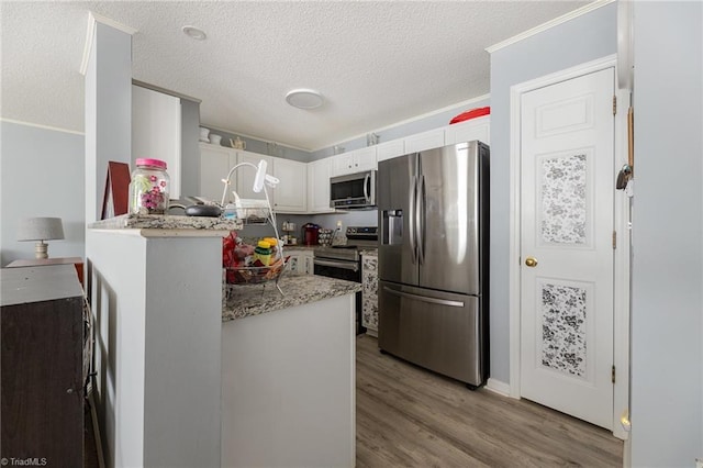 kitchen featuring appliances with stainless steel finishes, light stone countertops, light hardwood / wood-style floors, white cabinets, and kitchen peninsula