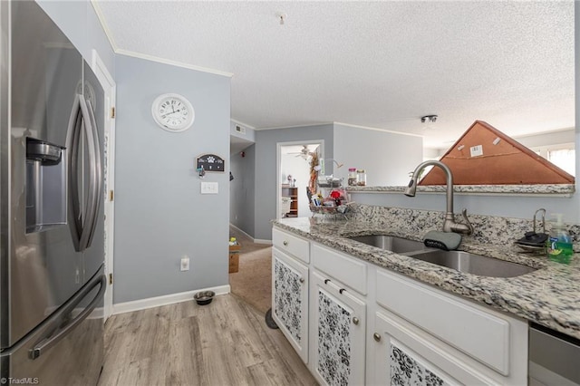 kitchen with stainless steel refrigerator with ice dispenser, white cabinetry, light stone countertops, and sink