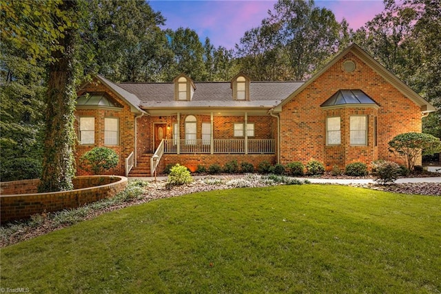 view of front facade featuring covered porch and a lawn