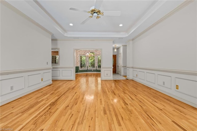 unfurnished living room with crown molding, light hardwood / wood-style flooring, and a raised ceiling