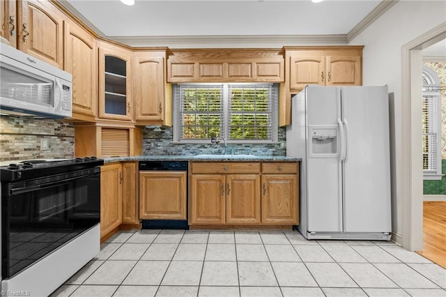 kitchen featuring dark stone countertops, a healthy amount of sunlight, sink, and white appliances