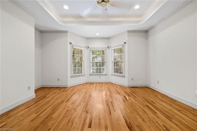 empty room with ornamental molding, light hardwood / wood-style floors, and a raised ceiling