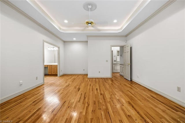 unfurnished bedroom with light hardwood / wood-style floors, crown molding, a raised ceiling, and ensuite bath