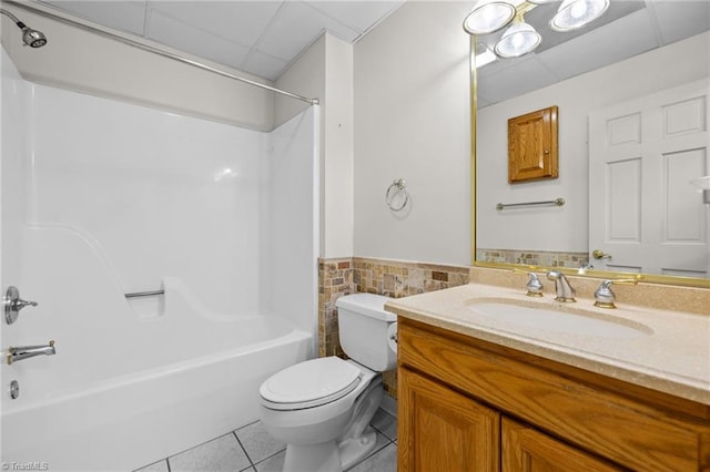 full bathroom featuring bathing tub / shower combination, toilet, tile patterned floors, tile walls, and vanity