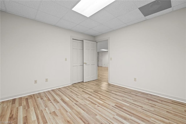 empty room featuring a drop ceiling and light hardwood / wood-style flooring