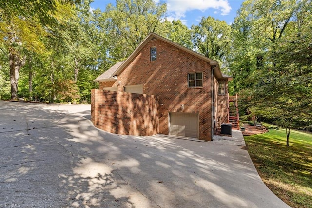 view of side of property featuring central air condition unit, a yard, and a garage