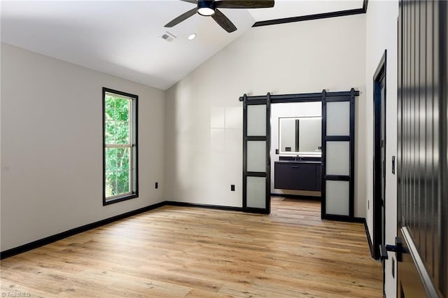 6376 Welborn Rd, Trinity, NC 27370 - unfurnished room featuring a ceiling fan, light wood-style flooring, a barn door, and high vaulted ceiling