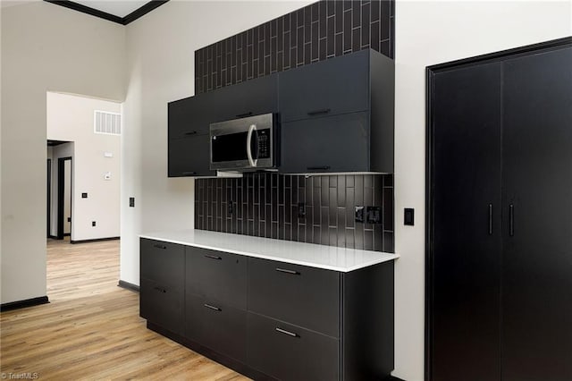 6376 Welborn Rd, Trinity, NC 27370 - kitchen featuring stainless steel microwave, dark cabinets, light countertops, light wood-style floors, and a high ceiling